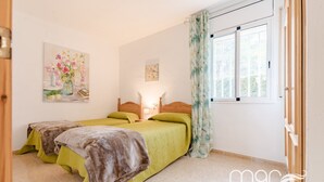 Une chambre avec deux lits, une fenêtre avec des rideaux et un tableau au mur.