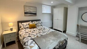 A bedroom with a bed, a nightstand, a radiator, a wardrobe, and a window with blinds. - Inviting 1-bed Apartment in Banbury (Banbury)