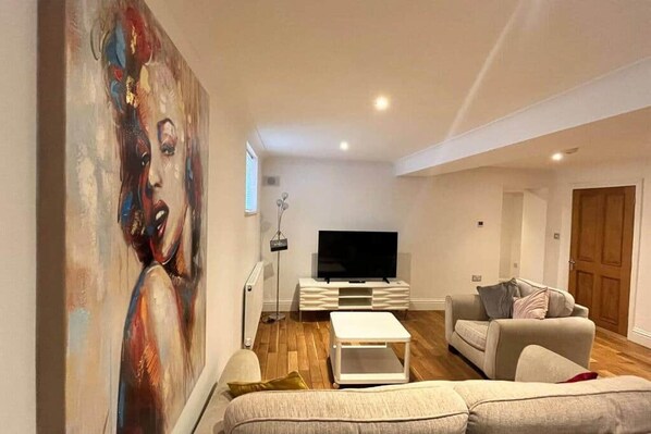 A modern living room with a large painting, a flat-screen TV, a white coffee table, and a sofa.