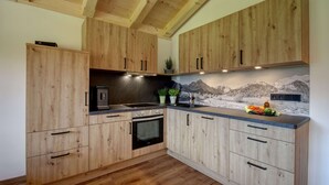 Una cocina moderna con armarios de madera, horno integrado y salpicadero de piedra que representa un paisaje montañoso.