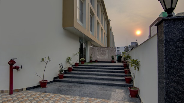 A staircase leading to a building entrance with potted plants and a red fire hydrant. - Treebo Torque (Greater Noida)