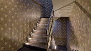 A staircase with patterned wallpaper and metal railings. - Treebo Torque (Greater Noida)