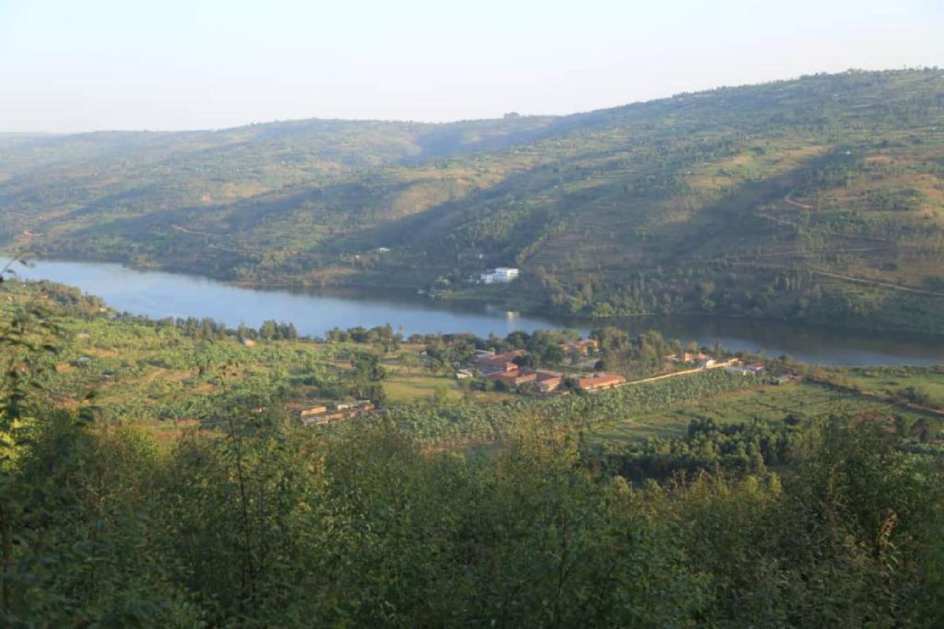 A rural landscape with a lake, surrounded by hills and scattered houses.