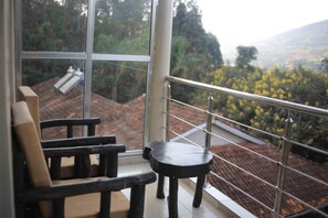 Un balcon donnant sur un toit recouvert de tuiles et sur des arbres.