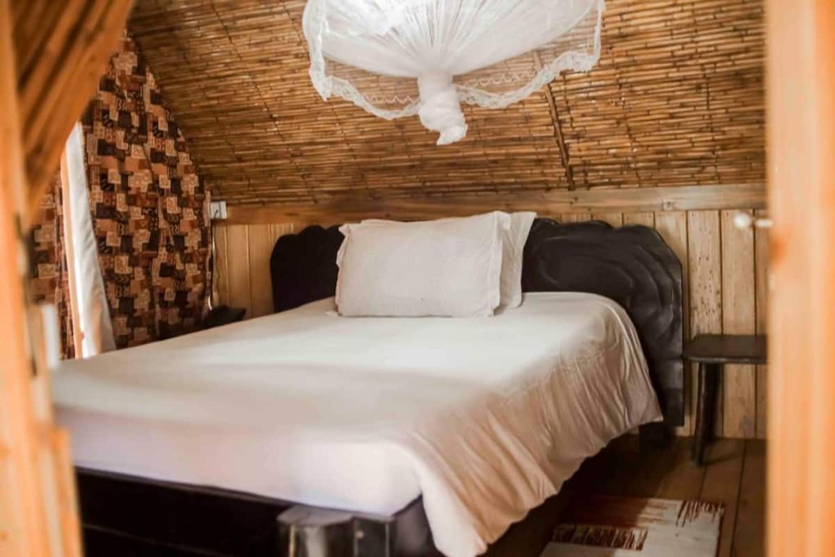 A room with a bed, a small table, and a woven wall.