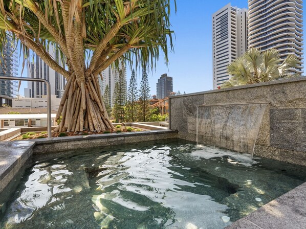 Relax by the serene pool surrounded by lush greenery and modern city views.