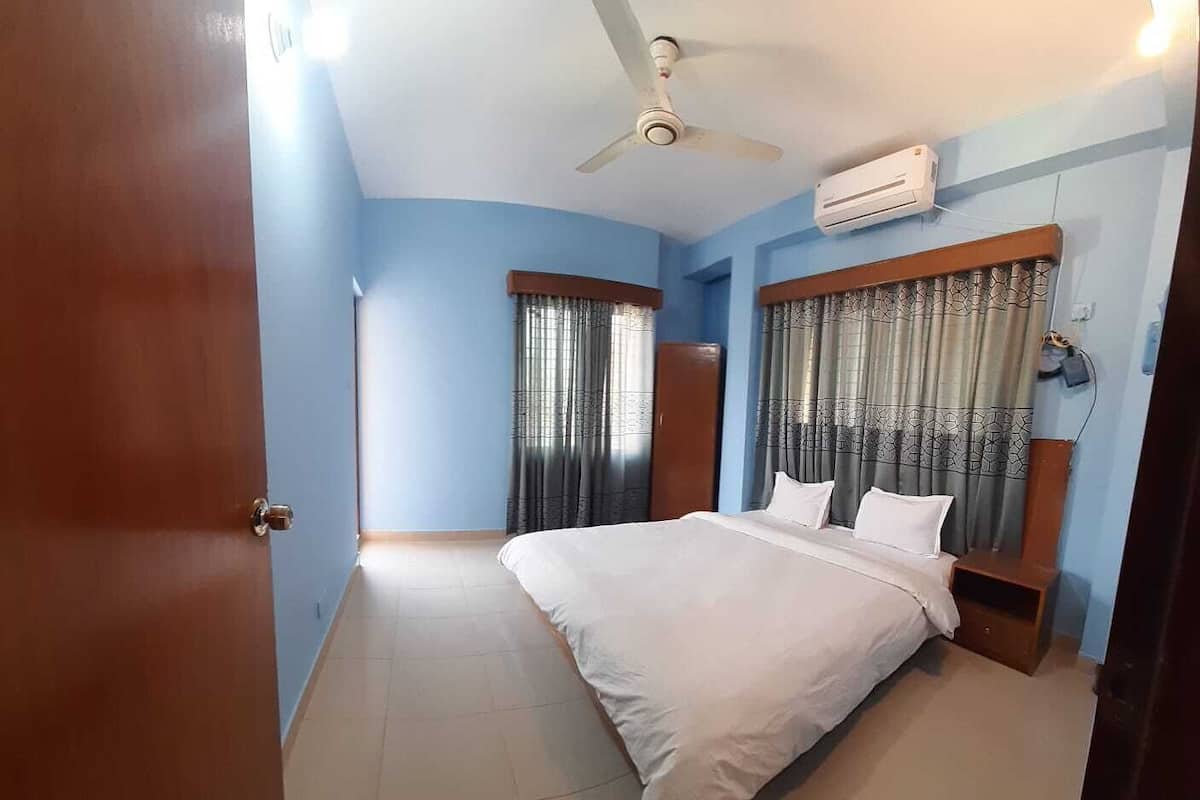 Quarto com cama, ventilador de teto, ar condicionado e cortinas.