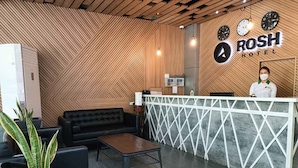 Un espace d’accueil agrémenté d’un mur en bois, d’un comptoir de réception, d’un canapé en cuir noir, d’une table basse et d’une plante en pot.