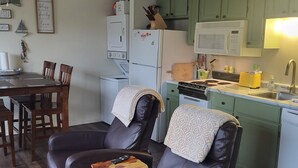 A cozy living room with a leather sofa, a dining table, and a kitchen area with green cabinets and a microwave. - Lakeside, fishing, Cozy 2/2 - 5 minutes from Branson attractions and Table Rock (Branson)