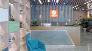 A hotel reception area with a reception desk, a blue chair, and a reception sign.
