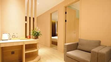 A room with a desk, a sofa, a bed, and a sliding door leading to another room.