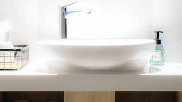 A white bathroom sink with a modern faucet, a soap dispenser, and a small container on the countertop.