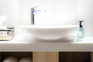 A white bathroom sink with a modern faucet, a soap dispenser, and a small container on the countertop. - Manring Hotel (Lijiang)