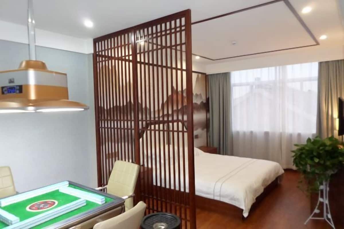 Ein Hotelzimmer mit Bett, Schreibtisch mit Computer, einem dekorativen Raumteiler und Blick auf die Stadt.