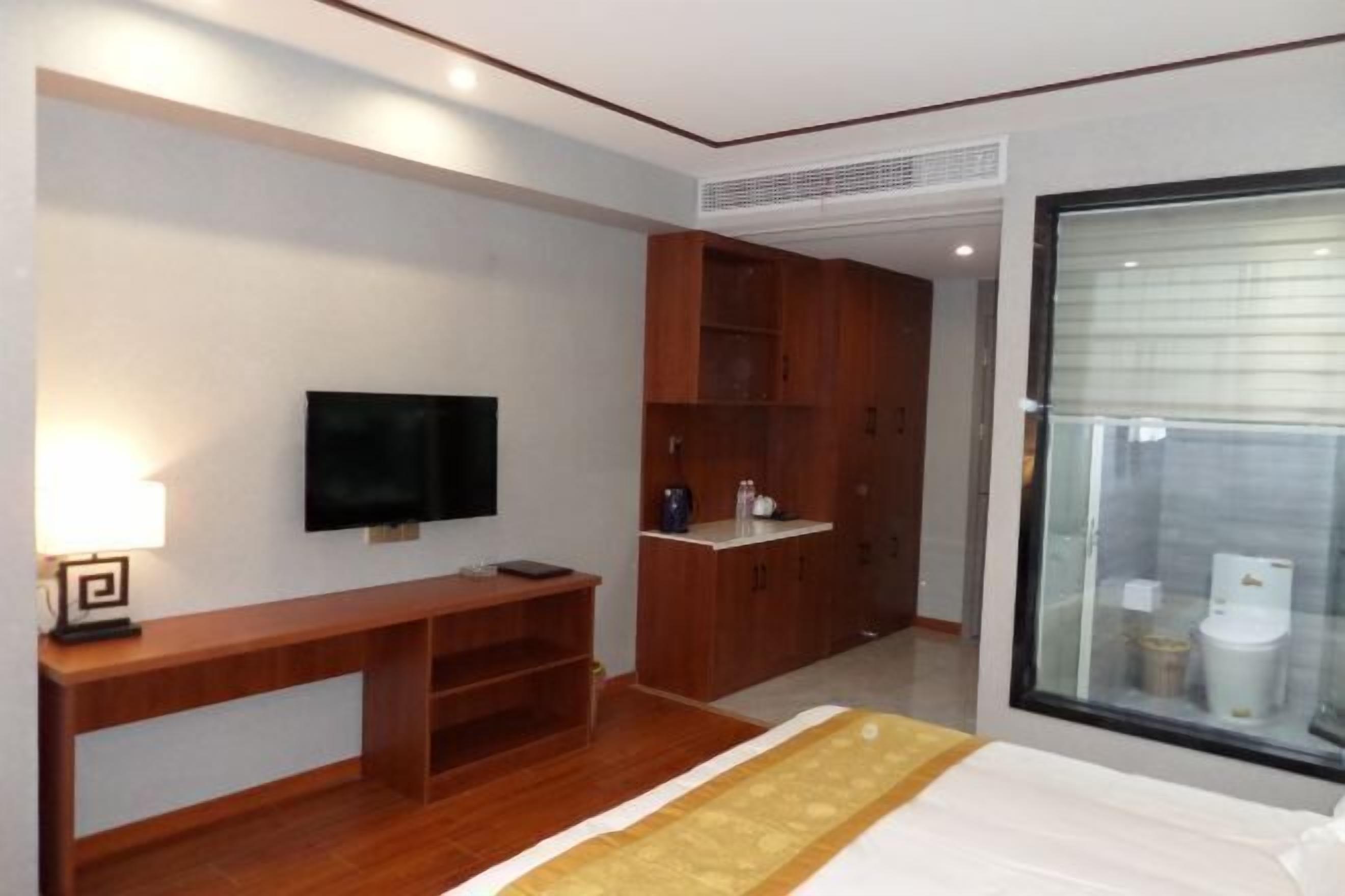 Ein Hotelzimmer mit Bett, Fernseher, Holzschreibtisch und Kleiderschrank.