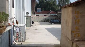 A narrow alleyway with a concrete floor, a white building on the left, and a beige wall with yellow text on the right.
