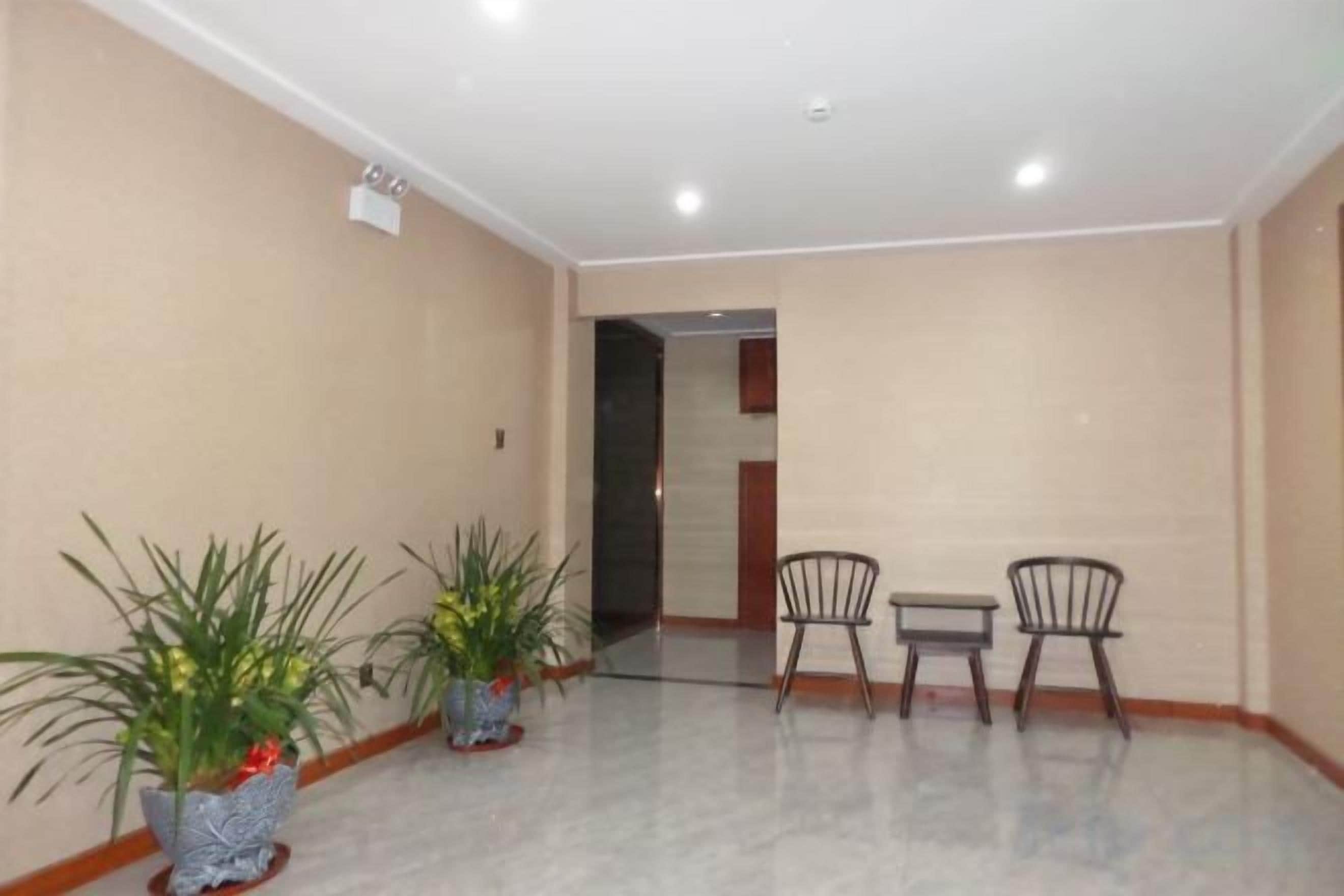 A room with a marble floor, two chairs, a small table, and potted plants.