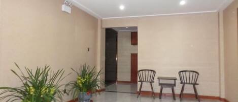 A room with a marble floor, two chairs, a small table, and potted plants.