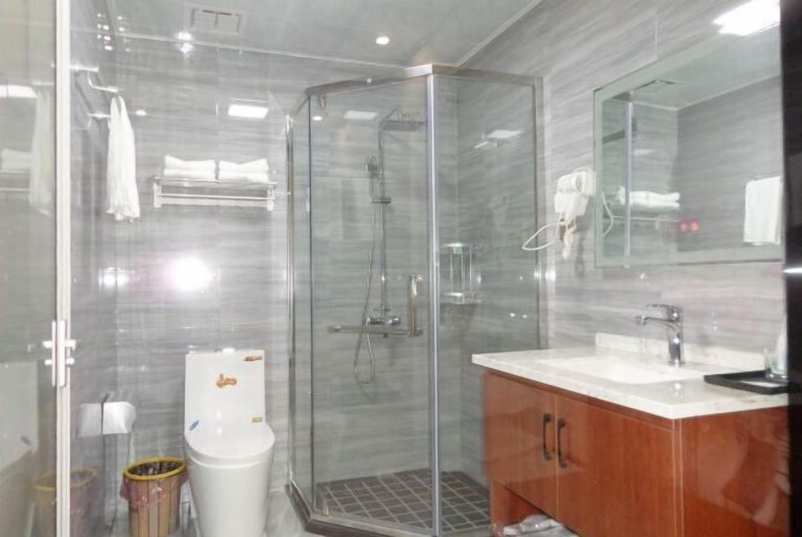 Ein modernes Badezimmer mit einer in Glas abgeschirmten Dusche, einer weißen Toilette und einem Holzwaschtisch.