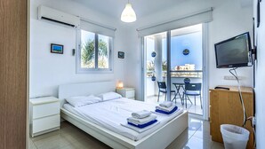 A modern hotel room with a bed, bedside tables, a desk, and a television.