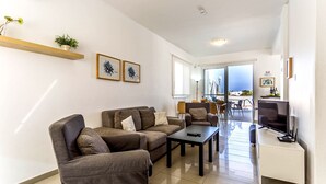 A modern living room with a sofa set, a coffee table, and a TV on a stand.