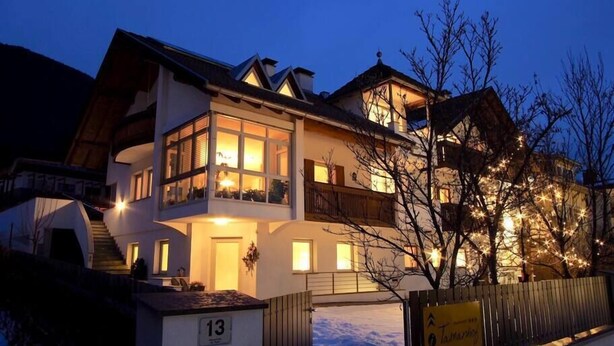 A two-story hotel with a balcony on the upper floor, a mailbox with the number 13, and a sign for 'Tamaris Hotel'. - Cozy appartment with great mountan view (Bruneck)