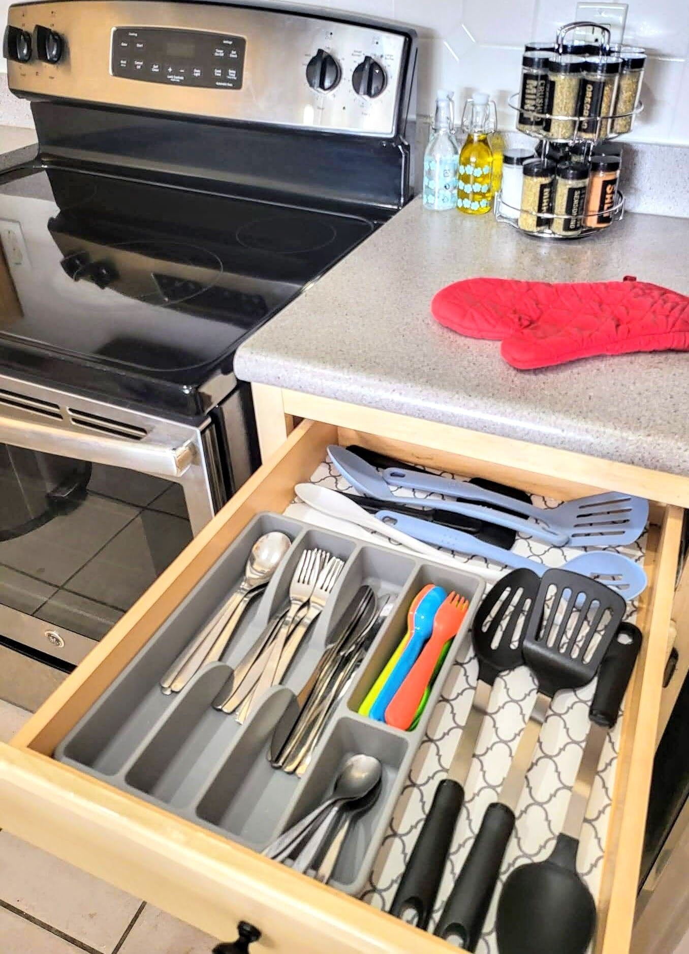 Een keuken met een fornuis, oven en een lade met keukengerei.