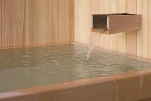 Una sauna de madera con un banco de madera y una fuente de agua.