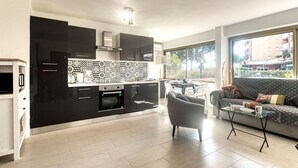 A modern kitchen with black cabinets, a patterned backsplash, and a dining area with a gray sofa and a glass coffee table.