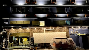 A multi-story hotel with a modern design, featuring balconies on each floor, a covered carport, and a reception area with seating. - Anandpura Riverside Hotel (Bangkok)