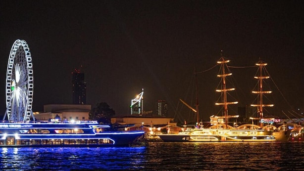 A waterfront scene with a Ferris wheel, a tall ship, and illuminated boats. - Anandpura Riverside Hotel (Bangkok)