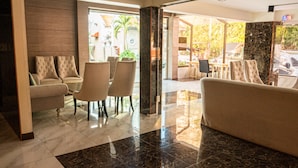 A lobby with a seating area, a reception desk, and a view of the outside. - Anandpura Riverside Hotel (Bangkok)