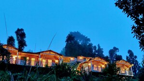 A series of wooden cabins with multiple rooms, surrounded by dense vegetation and trees. - Treehouse Resort (Dhari)