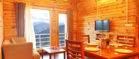 Una cabaña de madera con comedor, sofá y televisor.