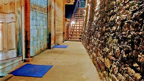 A narrow pathway leading to a wooden building with a stone wall on one side. - Treehouse Resort (Dhari)