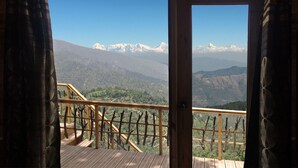 A wooden balcony with a metal railing overlooking a mountainous landscape with snow-capped peaks. - Treehouse Resort (Dhari)