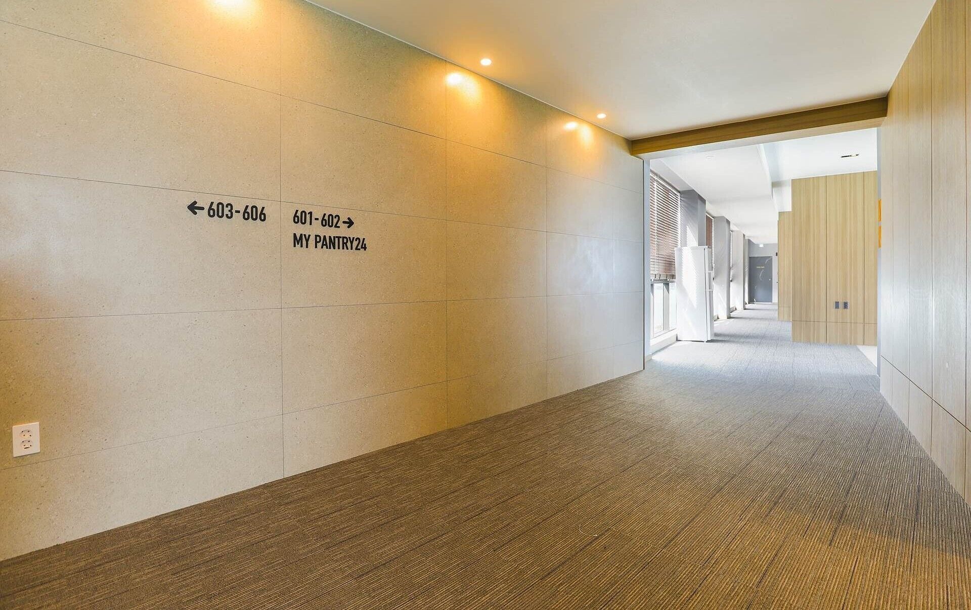 A hallway with directional signs to the pantry and a refrigerator.