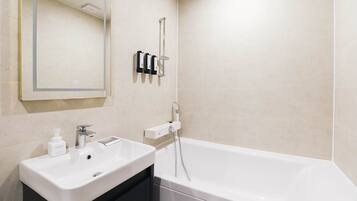 Een moderne badkamer met een wit wastafelmeubel, een spiegel, een handdouche en een bad.