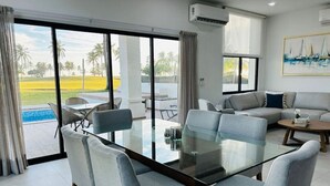 A modern living room with a glass table and grey upholstered chairs, a sofa, and a painting on the wall. - Hermosa casa vacacional (Mazatlán)
