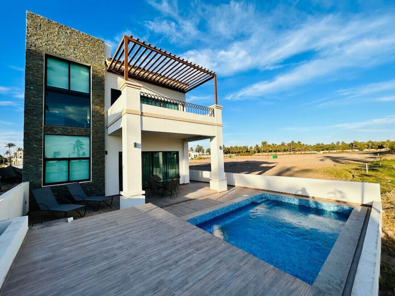A modern house with a swimming pool, a covered patio, and a view of a golf course.