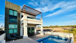 A modern house with a swimming pool, a covered patio, and a view of a golf course. - Hermosa casa vacacional (Mazatlán)