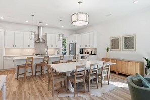 Una cocina moderna con armarios blancos, una isla central e iluminación colgante.