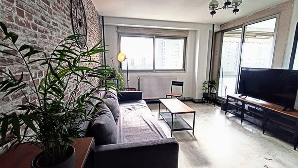 A living room with a sofa, a coffee table, a TV, and a large window.