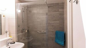 A modern bathroom with a glass-enclosed shower, a sink, and a toilet.
