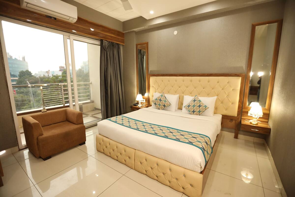 Een hotelkamer met een groot bed, een bank, een balkon en uitzicht op de stad.