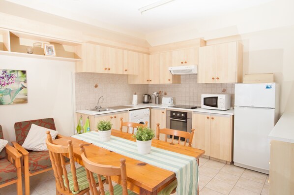 Una cocina compacta con armarios de madera, una mesa de comedor con sillas y un refrigerador.
