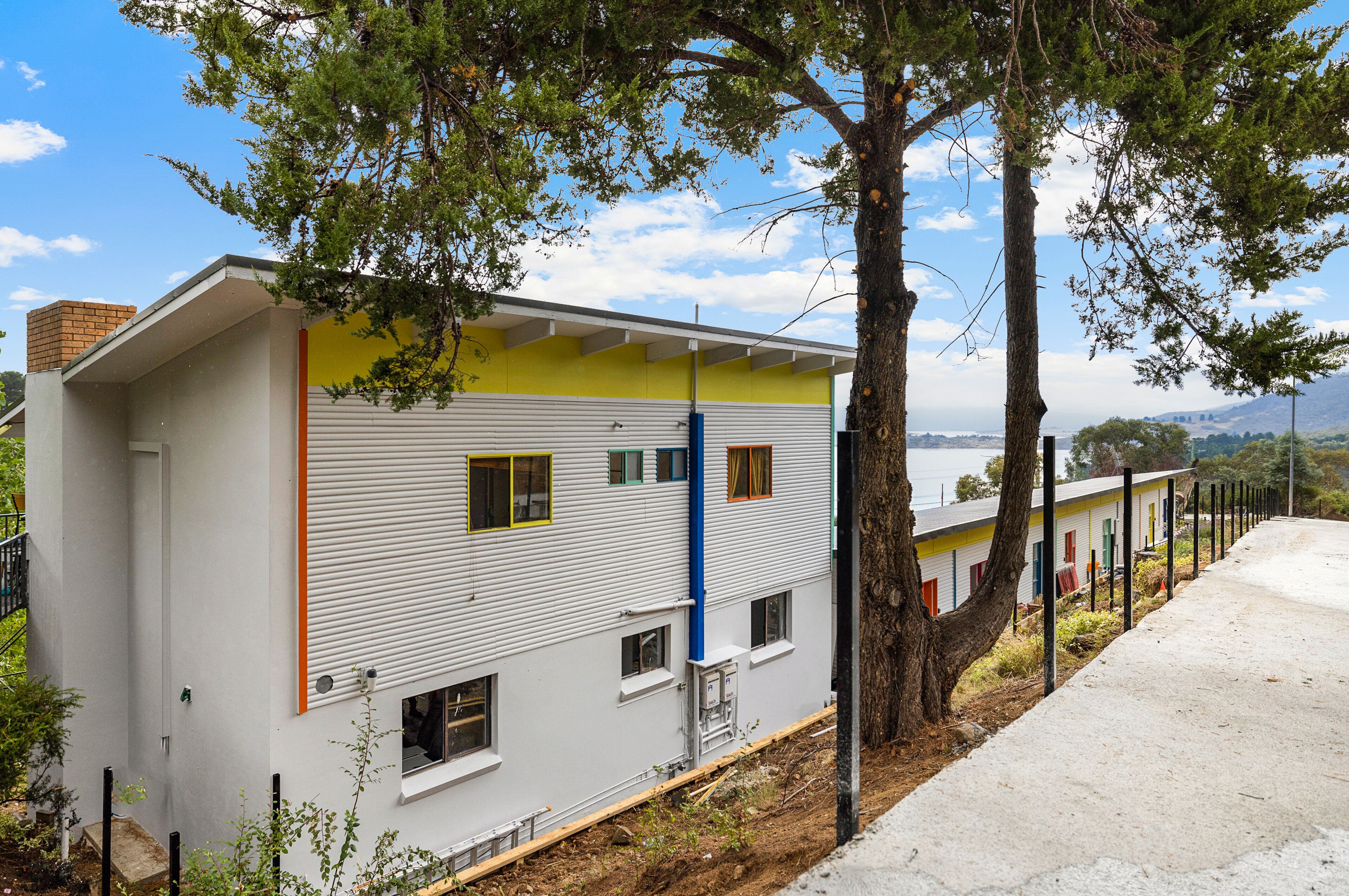 A modern building with a white exterior, multiple windows, and a visible blue pipe.