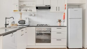 A modern kitchen with white cabinets, a built-in microwave, a gas stove, and a white refrigerator. - Alps Lakeview Lodge (East Jindabyne)