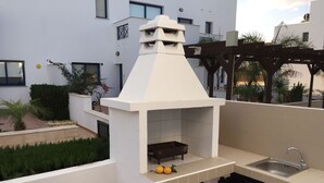 An outdoor kitchen area with a built-in grill, a sink, and a small countertop. - One Bedroom Bungalow Deluxe - Flouressia Gardens (Protaras)