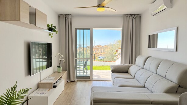 Ein modernes Wohnzimmer mit einer Couch, einem Fernseher und einem Balkon mit Blick.